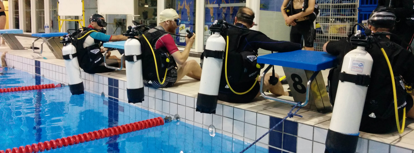 Des plongeurs qui s'apprêtent à effectuer une bascule arrière dans la piscine.